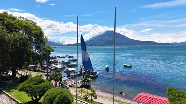 Beautiful cinematic aerial view os the Panajachel town surrounded by Toliman and Atitlan volcanoes, next to the Atitlan lake its piers and traditional fisher and tourist boats - Guatemala