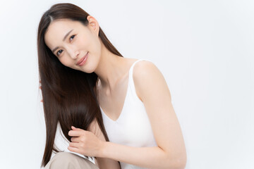Obraz premium 白バックでスキンケアをするロングヘアの若い女性