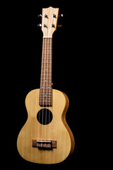 Naklejka premium a guitar, a light-colored ukulele on a black background. close-up.