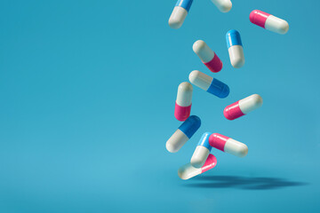 Falling pills on a blue background. Antibiotics A blue and pink pill is falling On a Isolated Blue Background