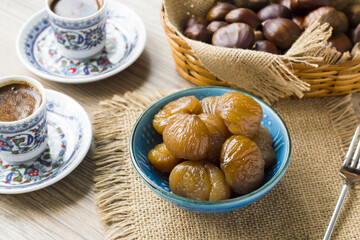 Traditional Turkish Candied Chestnuts designed in blue ceramic on wooden surface with coffee