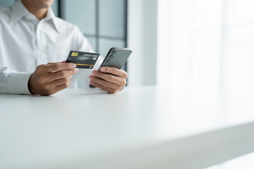Asian Man paying with credit card on smart phone at office. Male Using Smartphone for Shopping electronic wallet Online 