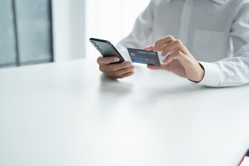 Asian Man paying with credit card on smart phone at office. Male Using Smartphone for Shopping electronic wallet Online 