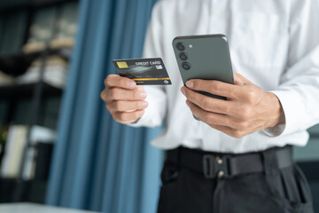 Asian Man paying with credit card on smart phone at office. Male Using Smartphone for Shopping electronic wallet Online 