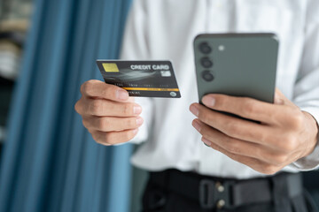 Asian Man paying with credit card on smart phone at office. Male Using Smartphone for Shopping electronic wallet Online 