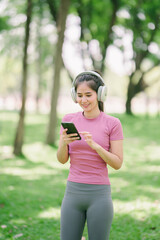 Sportswoman using smartphone app and walking on running track in the park.