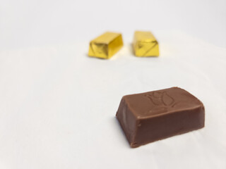 Chocolate candy unwrapped with golden wrapped candies in background