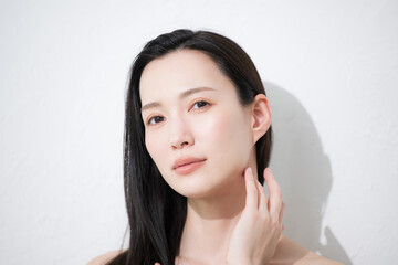 黒髪が美しい若い女性の艶と素肌感が美しい手を添えるビューティーイメージのカメラ目線でアンニュイな表情