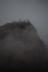 dramatic cliff scene in the evening, fog on the top of the mountains