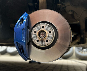 Car brake disc with blue caliper. Modern brake disc with holes and cooling. Brake disc and wheel...