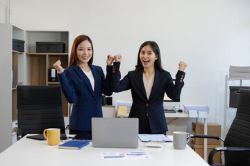 Excited businesswomen celebrating success, teamwork, and achievement in a modern office.