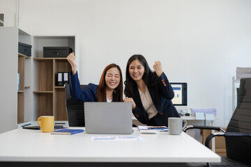 Excited businesswomen celebrating success, teamwork, and achievement in a modern office.