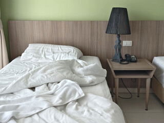 Wrinkled bed sheets and blanket on a bed.