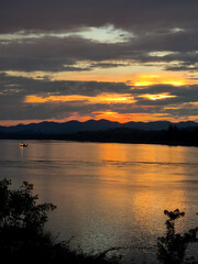 A beautiful orange sunset reflects on the calm lake water under the vast summer sky