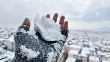 Snow gently sits on a hand overlooking a snowy cityscape