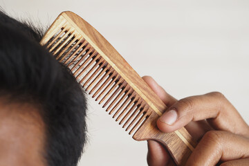 Person combing hair with a wooden comb in natural light setting