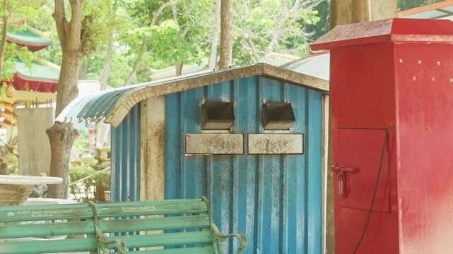 A wild macaque monkey jumps out of rubbish trash bin at Tiger Temple, Thailand. Highlighting human impact, this footage suits wildlife, travel, or environmental content.
