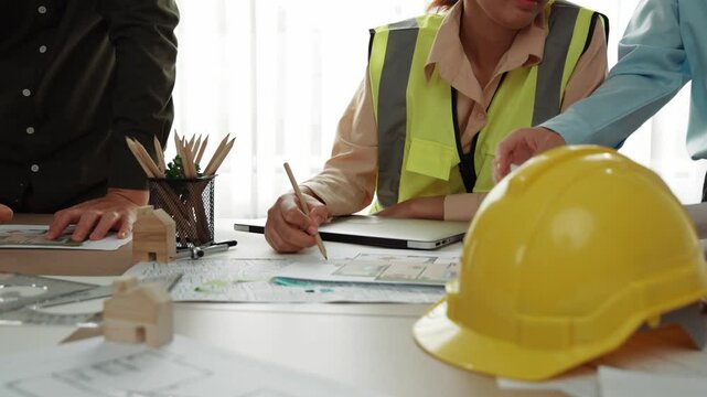 Professional engineer measuring the blueprint. Professional engineer working architectural project at studio on a table with yellow helmet and architectural equipment scatter around. Delineation.