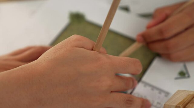 A video of architect using ruler and pencil to measure blueprint scale. Designer designing house construction on a table at studio with architectural plan scattered around. Focus on hand. Delineation.