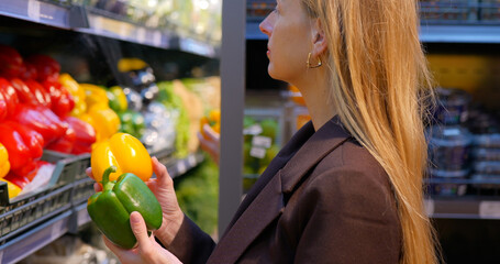 Woman selects bell peppers in grocery store produce section