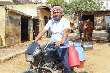 Rural Indian milkman sitting on bike at farm. People of india.