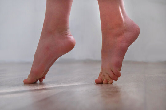 Barefoot teenage girl, dancer artist standing on tiptoe. Low section. Dance studio, tiptoe legs, position, practicing in ballet studio. Contemporary