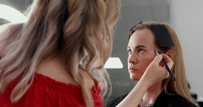 Businesswoman getting makeup done by makeup artist