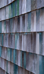 wooden shakes shingles on side of old building painted shades of green and fading vertical image taken from showing layers of individual wood squares of different colors vertical backdrop grey green