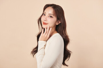 Fototapeta premium A beautiful young Asian woman with clean, fresh skin against a beige background. Skincare, facial treatment, cosmetology, beauty, and spa. An elegant portrait of an Asian woman.