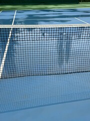 Wet hard tennis court surface. Matched are postponed or cancelled due to rain and water on court. Unplayable matches. Trees reflection in puddle