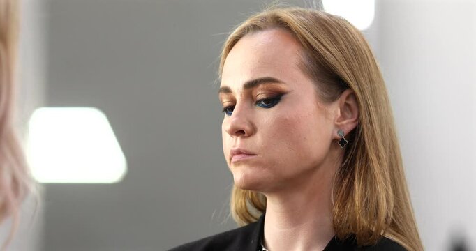 Businesswoman getting makeup done by makeup artist