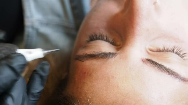 Extreme close-up in slow motion shows gloved hands performing eyebrow microblading with a fine-point tool highlighting in Every motion precision, steady control, and delicate cosmetic artistry.
