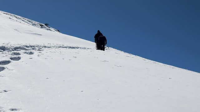 trekkers walking towards snow-covered mountain peak summit with bright sky at afternoon video is taken at Chopta Tungnath Himalayas mountain chandrashila trek uttarakhand india.