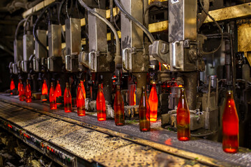 Glass factory, production of glass containers. Molten glass is blown into molds. Robotics in industry. Modern technologies, robotic machines produce products. Technological work at the plant.