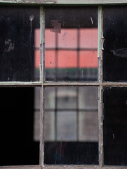 old wooden framed window on old abandoned building with reflecting another window and a building with a red roof rectangular shapes created by window frames black framing photos framed type space 