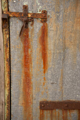 close up of rusty door handle  and metal hinge metal door with rust color dripping from old rustic exterior door rust and orange colored stripes vertical grungy wiht room for type backdrop background 