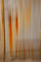 vertical abstract blur image of rust color orange and yellow rust dripping stripes on metal door concept created by long time exposure and intentional camera movement oxidization blurred background 
