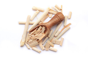 A wooden scoop filled with organic Lemongrass (Cymbopogon flexuosus), placed on a heap of lemongrass, isolated on a white background.