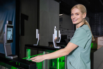 Female doctor in lab coat passing through security control by using access card