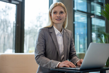 Female entrepreneur sitting on sofa working on laptop in office