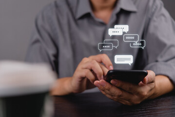 Hand holding smartphone with chat bubbles overlay. Digital network Social media online communication, instant messaging and online interaction concept.