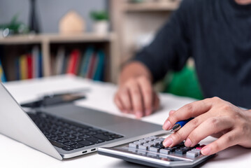 Person calculating expenses with calculator and laptop. Financial budget planning and money online...