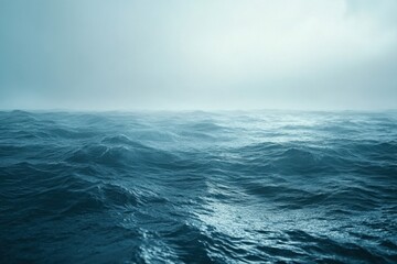 Ocean waves undulate under a misty sky at dawn near a tranquil coastline