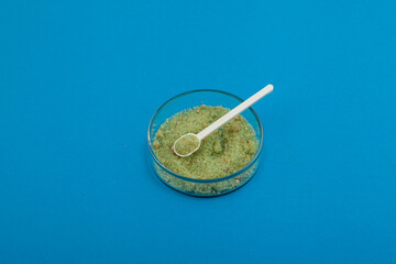 Iron sulfate powder or Green vitriol in Petri dish. Salt with chemical formula FeSO4. Fertilizer....