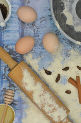 Baking ingredients for baking: flour, eggs, rolling pin, cake tin and delicacies on blue background. Top view blue, kitchen table.