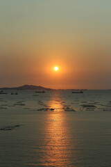 Obraz premium Sea is filled with cargo ships and fishing boats at dusk.