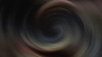 A blurry close up image showing a dark vortex with a white swirling shape in the center of the image