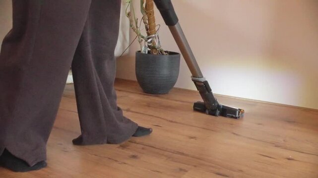 woman with wireless vacuum cleaning the living room in pyjamas. handheld slowmo.