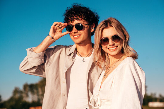 Smiling beautiful woman and her handsome boyfriend. Excited couple in casual clothes. Happy cheerful family. Female and man pose at sunrise over sea beach outdoors. Seaside in summer day