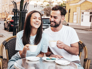 Smiling beautiful woman and her handsome boyfriend. Happy cheerful family. Couple drinking coffee in restaurant. They drinking tea at cafe in street. Holding cup. Enjoying their date. In sunglasses